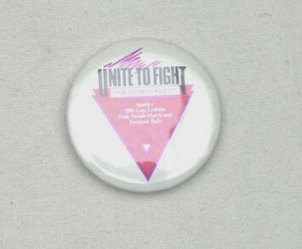 White badge with the text "UNITE TO FIGHT FOR HUMAN RIGHTS &nbsp;SEATTLE&nbsp;1986 GAY/LESBIAN PRIDE PRADE MARCH AND FREEDOM RALLY" over a pink triangle. USA, 1986.