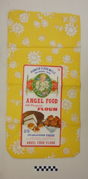 Flour sack made from bright yellow cloth with printed flowers, to be used for clothing or other domestic textiles. USA, 1960s.