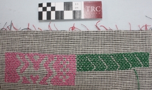 A white piece of canvas used as a guide for cross stitch embroidery on a ground cloth underneath. Jordan, 1970's.