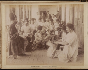 Photograph of embroidery workshop in Rasht, Iran, with man being bastinadoed. Dated c. 1880.