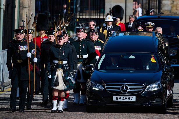 The hearse carrying the Queens coffin emerges from the gates of Holyrood Palace, guarded by the Royal Company of Archers. Copyright: Brian_D_Anderson/REX/Shutterstock