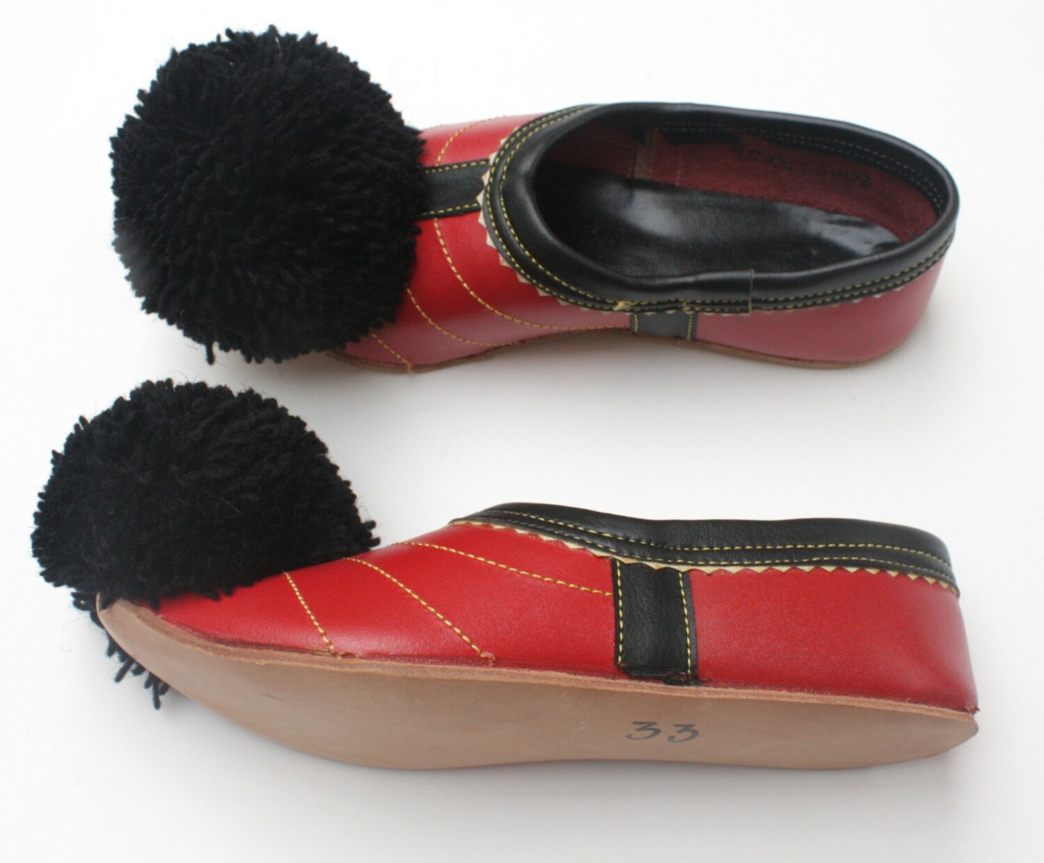 Pair of red leather shoes with big black pompoms at the toes, Greece, early 21st century (TRC 2005.0304a b).