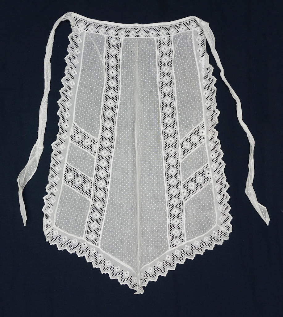Fig. 4. White apron decorated with small white dots and bands of machine embroidered flower heads and zig-zags. Germany, 20th century (TRC 2016.0874).