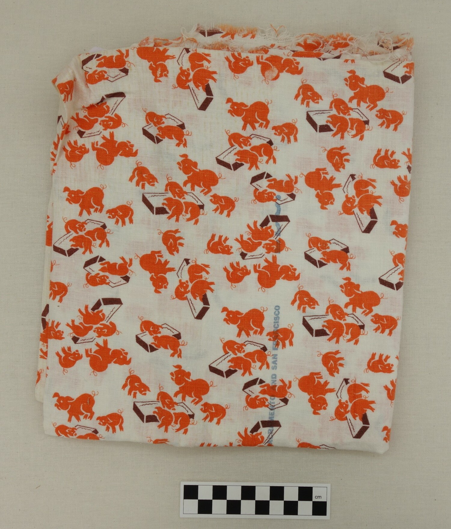 Feed sack cloth, folded in half, with a design of orange pigs of various sizes eating at brown troughs. 1940s, USA (TRC 2017.1366).