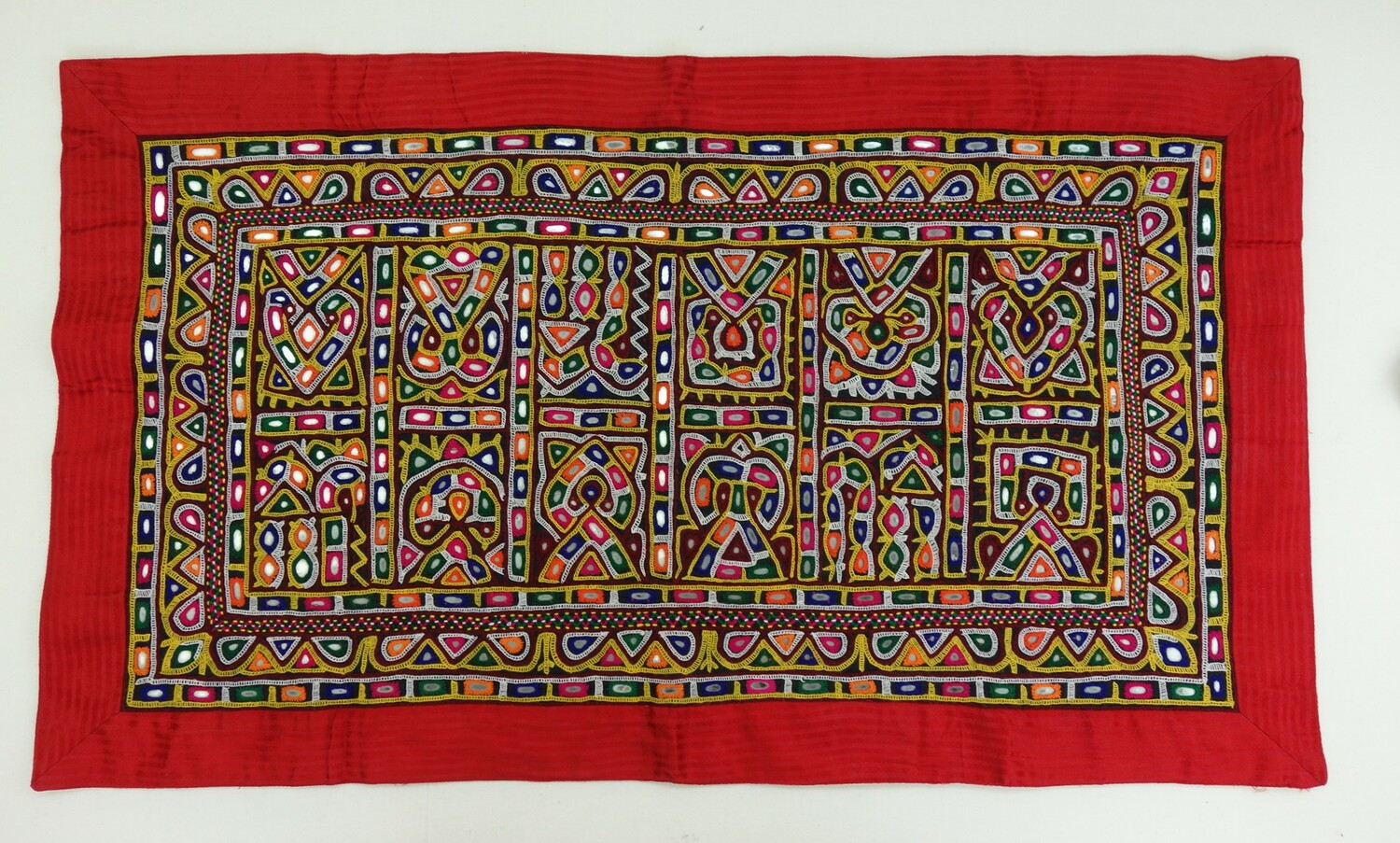 Rectangle of cloth embellished with geometric and highly stylised human figures in various colours. There are also small glass mirrors (shisha work) at regular intervals. India, 2017 (TRC 2017.2653).