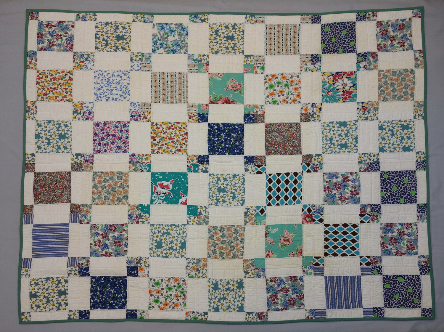 Quilt made from feedsacks. The design is made up of large and small squares of patterned cotton alternating with white cloth (flour sacks). USA, 1930s, 2011 (TRC 2017.4292).