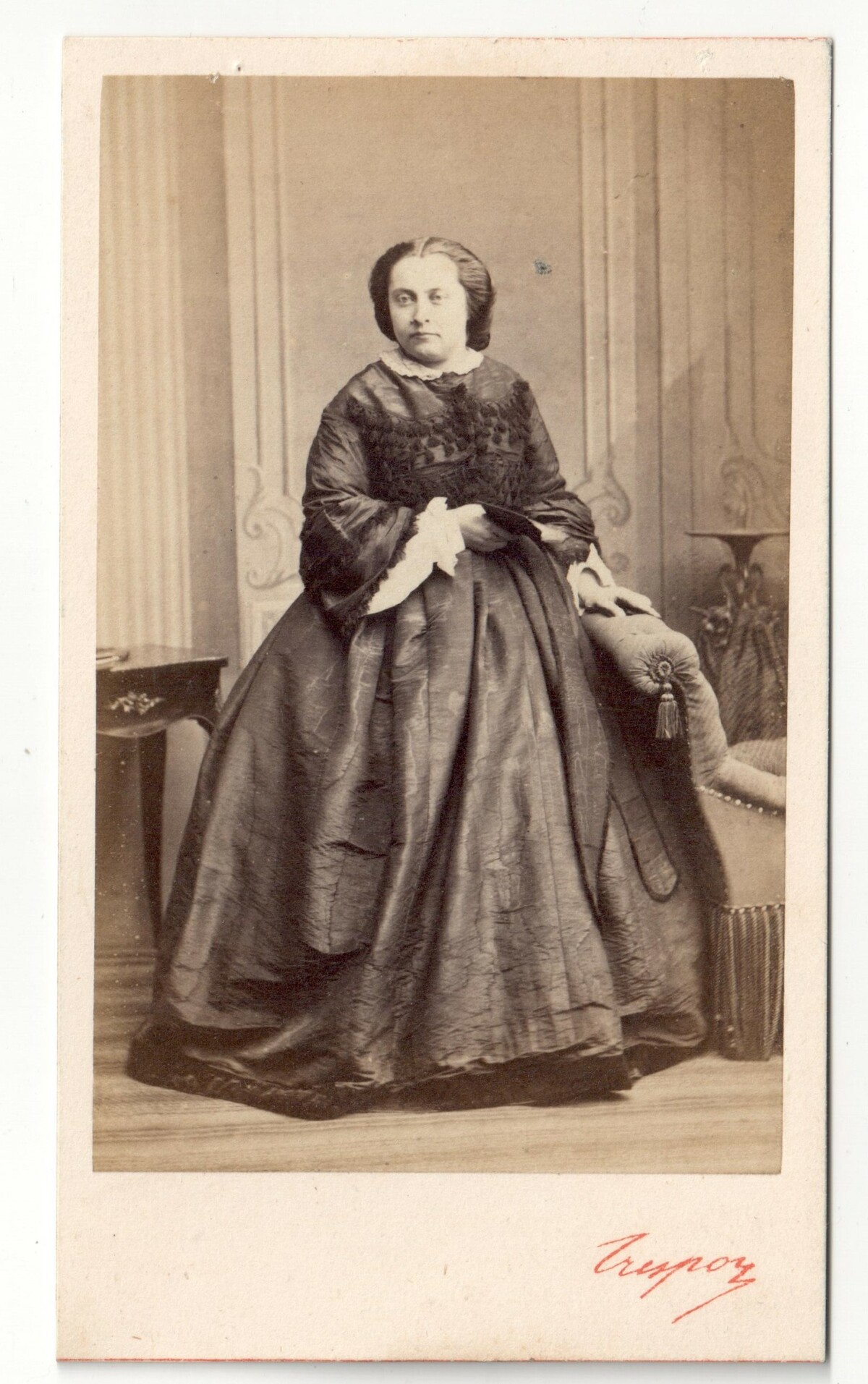 Photograph from France, mid-19th century, of a standing woman wearing a dark coloured crinoline dress with large bell shaped sleeves and white engageantes (TRC 2018.3329).