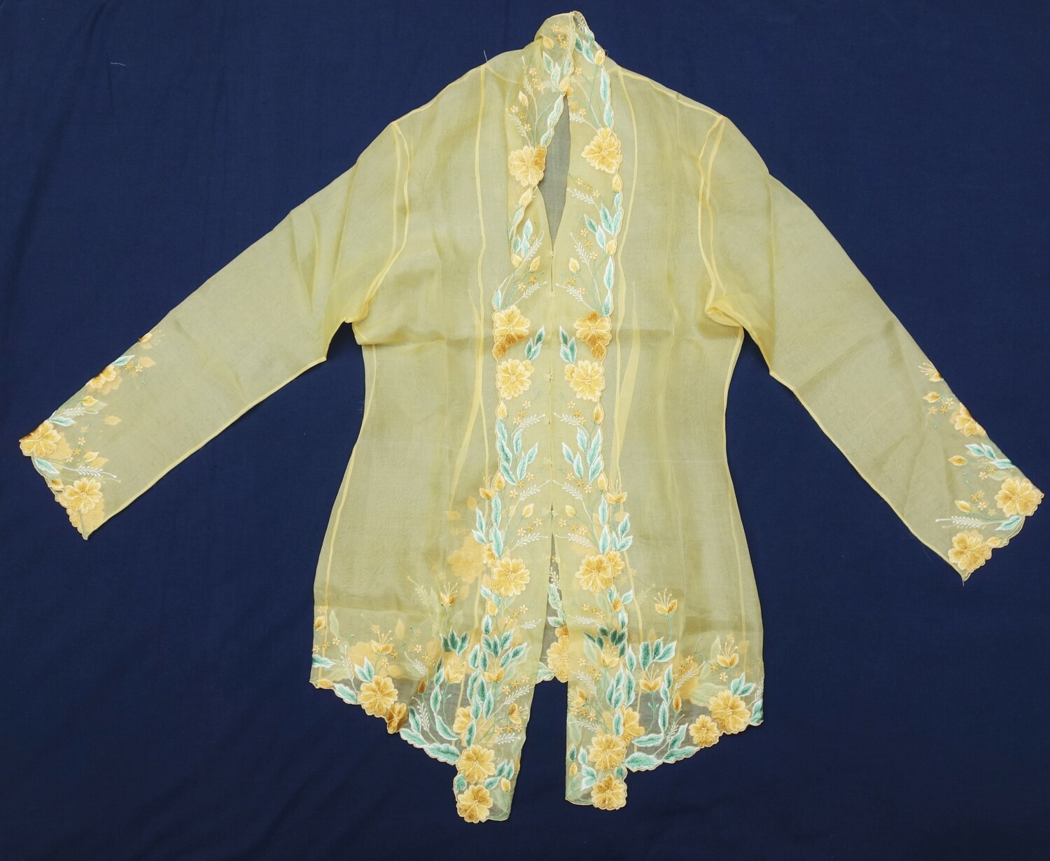Long women's blouse (kebaya) in a pale yellow chiffon, machine embroidered, Indonesia, 20th century (TRC 2023.0554).