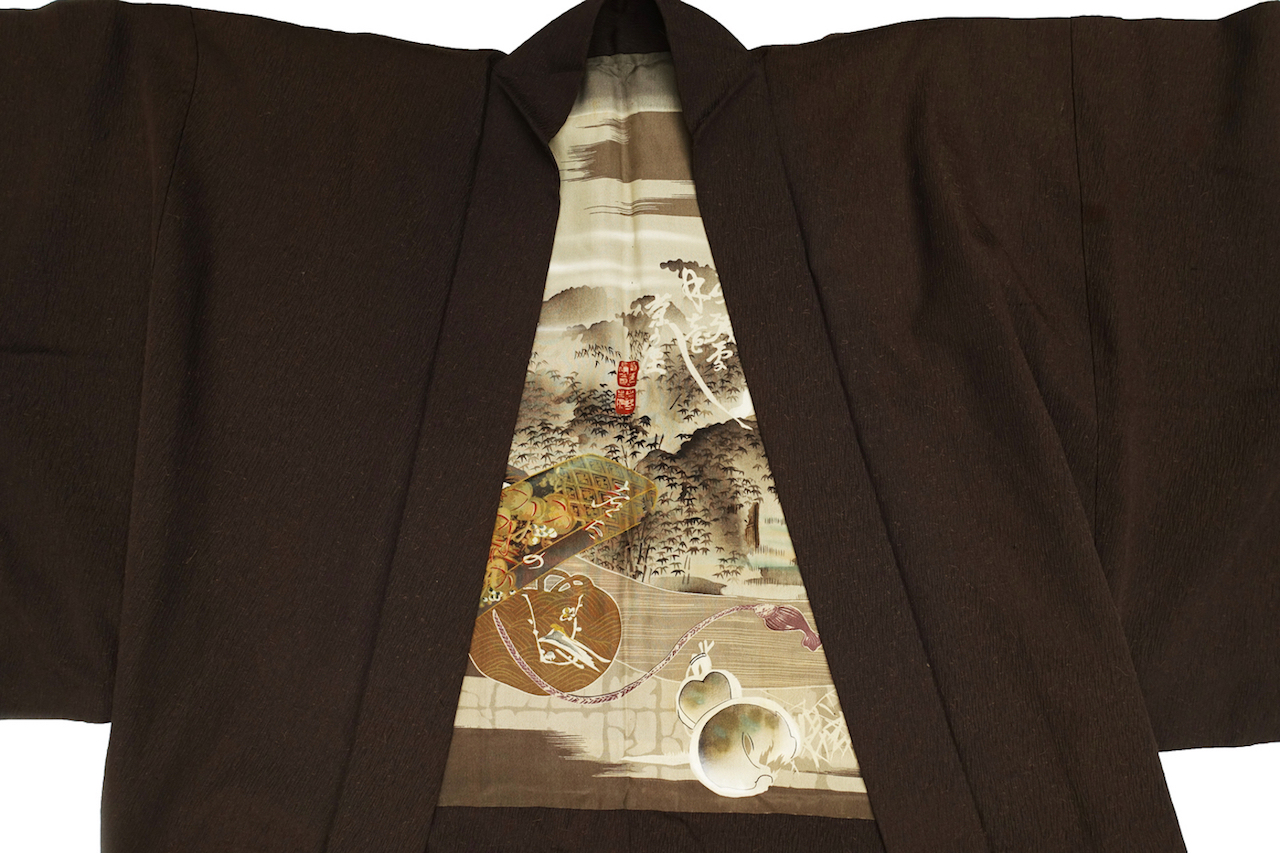 Inside of a man's haori, decorated with a painted design of a stylised landscape with various motifs, including a curled up, sleeping cat. Japan, 20th century (TRC 2024.1065).