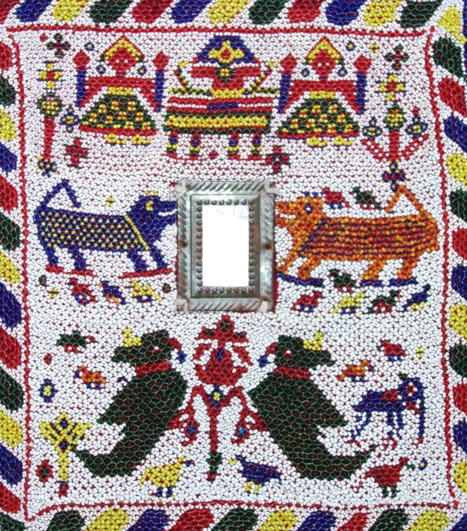 Beaded panel with applied glass mirror (shisha work) and three stylised figures of Hindu gods, elephants, birds and floral motifs, all in various colours on a white ground. India, 20th century. Donated by Marjolijn van Scherpenzeel. TRC 2024.3153 2