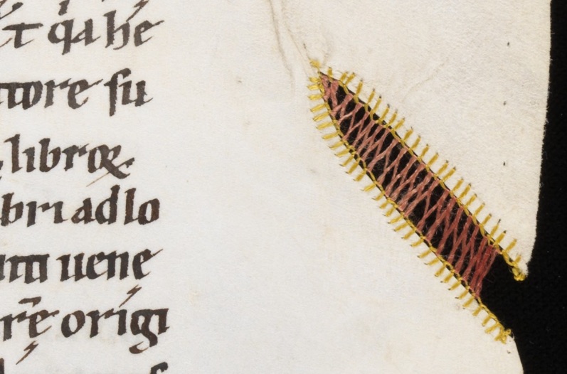 Open buttonhole stitch (blanket stitch) in yellow used as an edging around the hole, to act as an anchor for a line of Cretan stitch in brown that was used to strengthen a parchment gap (Engelberg, Stiftsbibliothek / Cod. 22 – Gregorius M., Moralia in Job, t. III / f. 24r).