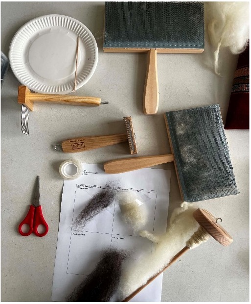 Fig. 2. Learning how to card raw wool before spinning it into yarn. Photograph by author.