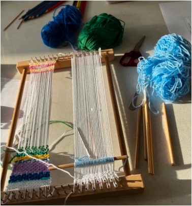 Fig. 3. Learning basic weaving techniques on a tabletop loom. Photograph by author.