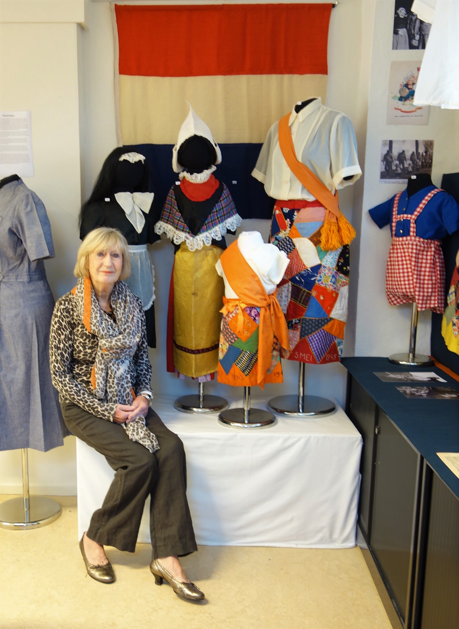 Mw Tineke van der Staaij, 81 years old, sitting in front of the Volendam-style outfit (with the characteristic white cap) made for her by her mother when she was six years old. She wore the garments at a liberation parade in Leiden (May 1945).