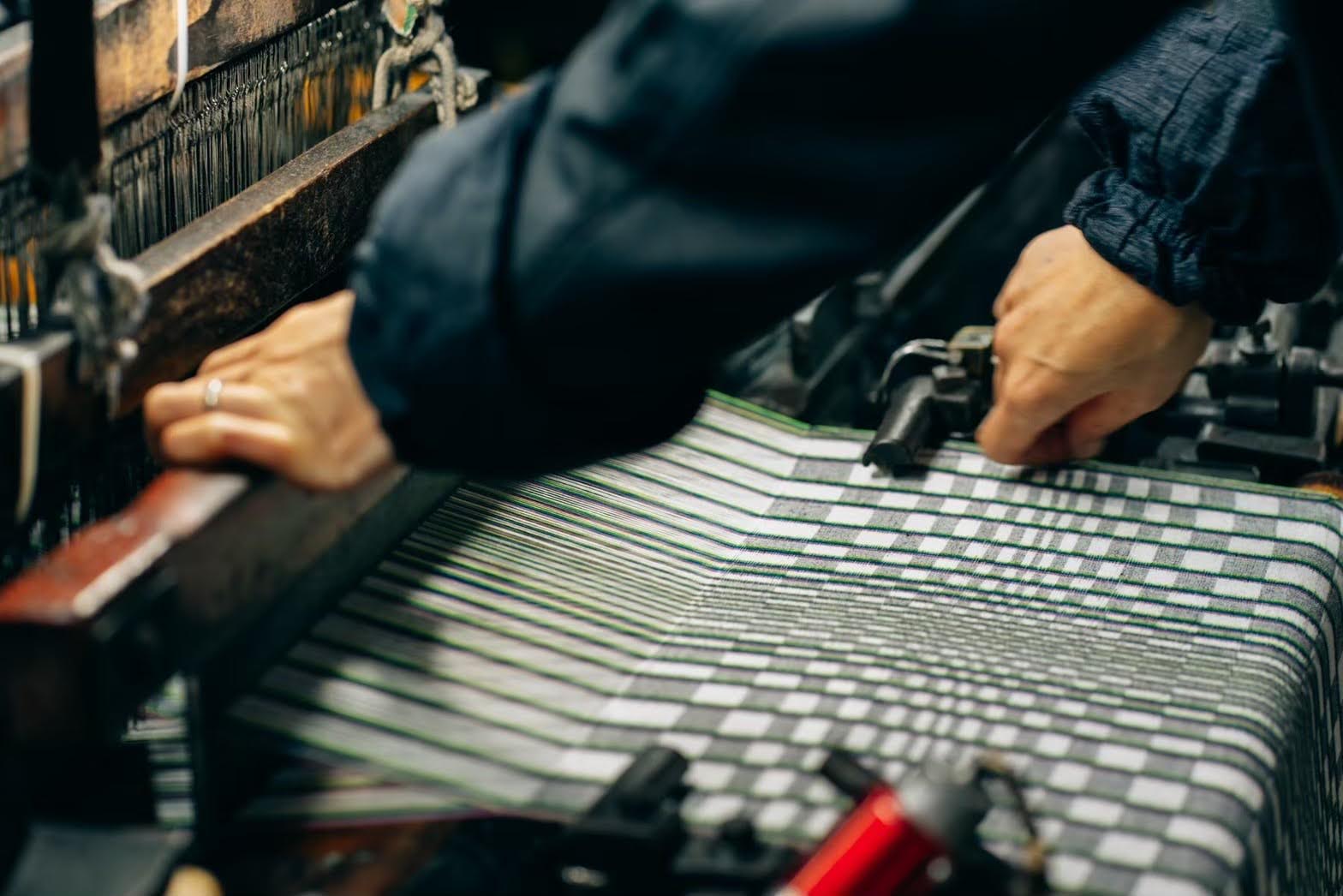 Inside the Shimogawa Orimono workshop, twenty narrow-width vintage power looms are driven by a single motor, their shuttles moving back and forth to weave the carefully prepared kasuri threads. Photograph: www.hanatextiledesign.com