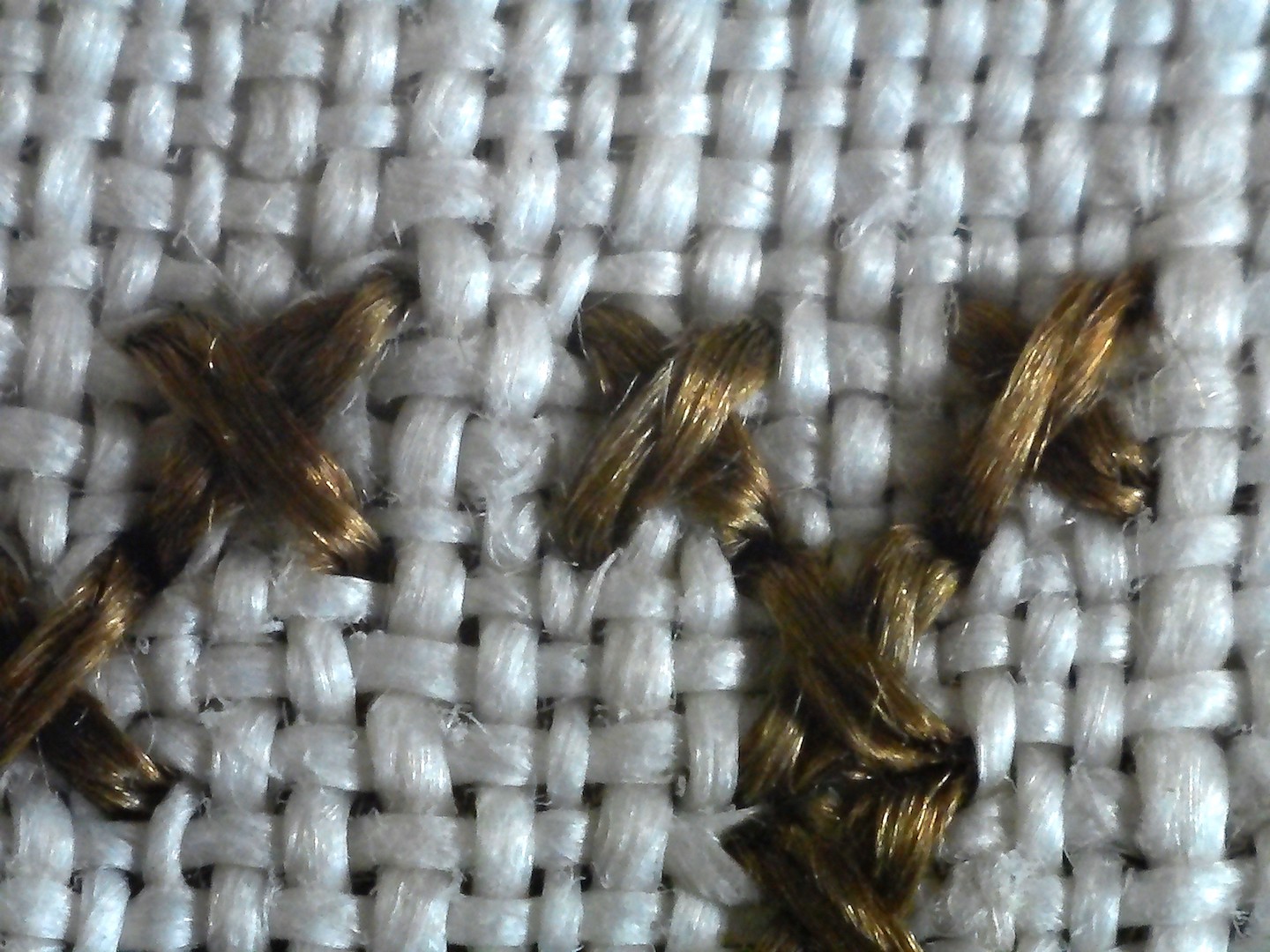 Close-up photograph of the linen ground and the dark brown cross stitches.