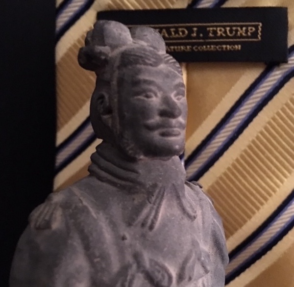 Statue from the tomb of the Chinese emperor Qin Shi Huang (died c. 210 BC) of a terracotta soldier with neckband. In the background a tie label from President Donald Trump's fashion line of ties (coincidentally made in China).